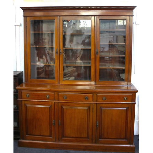 427 - An Edwardian walnut bookcase, the upper section with shaped cornice above three glass panelled doors... 