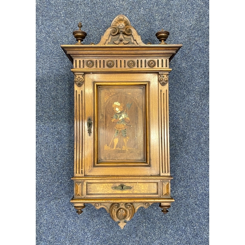 895 - A wall cabinet the single panel door inlaid with a figure of a knight in bone and mother of pearl, 9... 