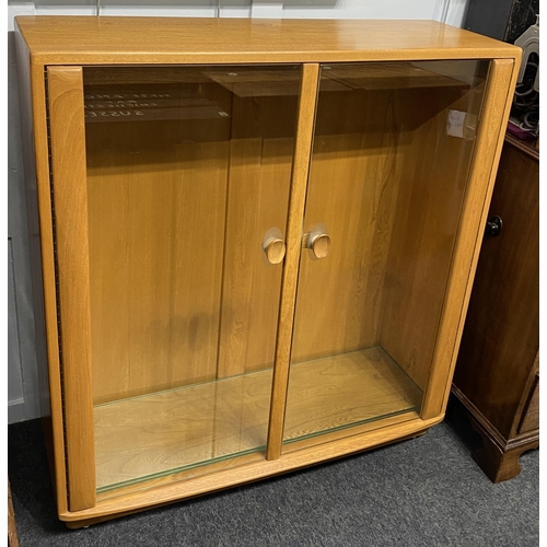 903 - An Ercol pale elm and beech display cabinet with two glazed doors enclosing glass shelves, height 10... 