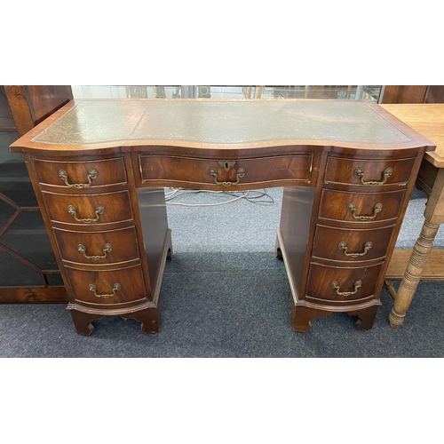 910 - A vintage mahogany shaped front pedestal desk in the 19th century taste, having a gilt tooled green ... 