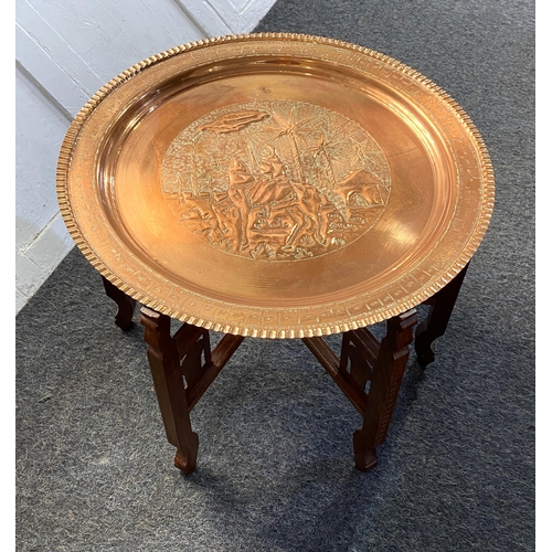 920 - An early / mid 20th century Middle Eastern brass top nomadic coffee table on folding wooden base, de... 