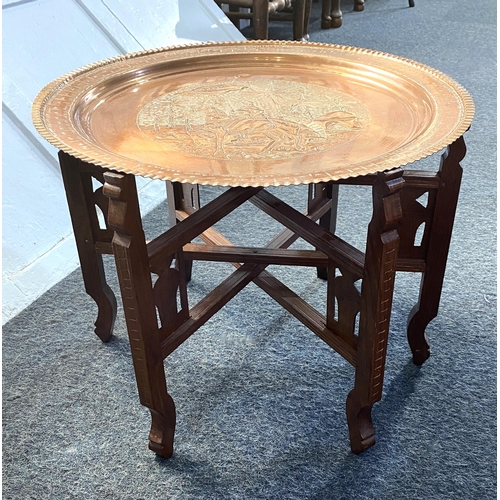 920 - An early / mid 20th century Middle Eastern brass top nomadic coffee table on folding wooden base, de... 