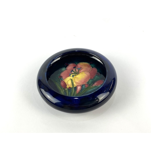 38 - A Moorcroft 'African Lily' patterned dish, decorated against the dark blue ground with tube lined fl... 
