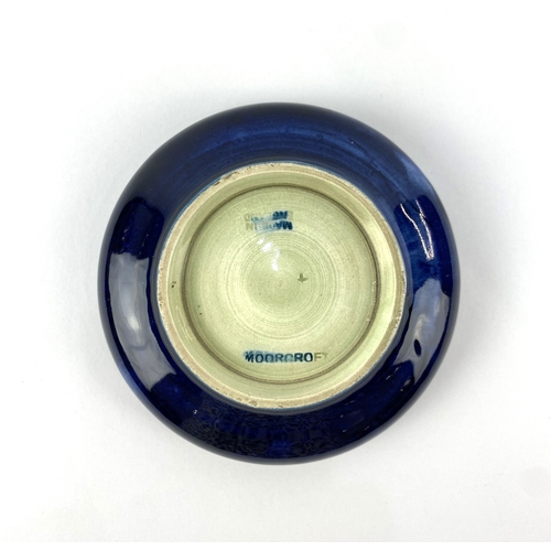 38 - A Moorcroft 'African Lily' patterned dish, decorated against the dark blue ground with tube lined fl... 