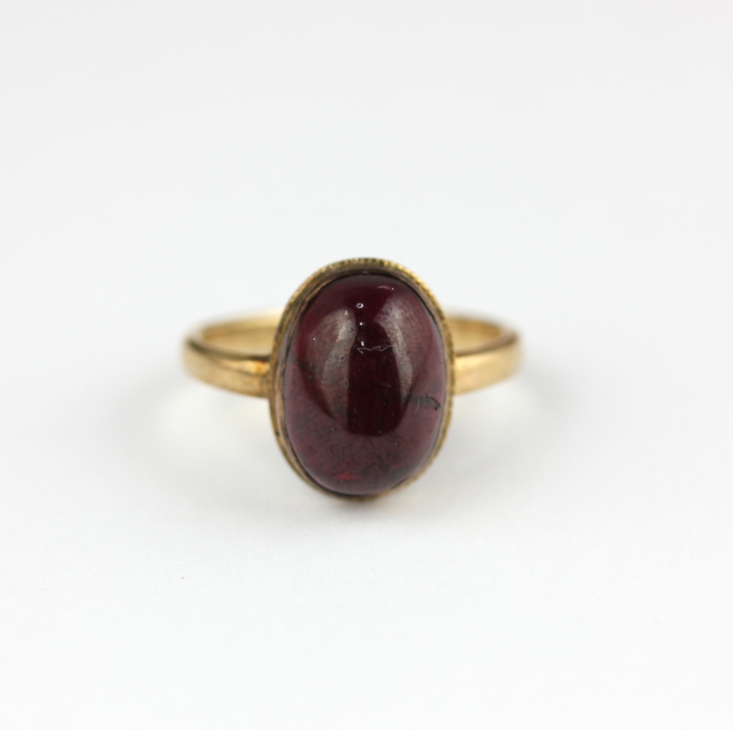 A 9ct gold ring collet set with an oval carbuncle garnet, Sheffield ...
