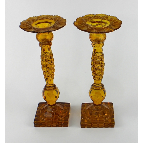 1 - A pair of 19th century amber coloured glass candlesticks, with faceted decoration throughout, 33cm h... 