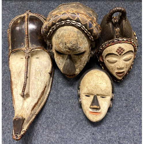 132 - Four large African face masks to include a Fang Ngil mask 57cm long, a Dan style helmet mask 31cm an... 