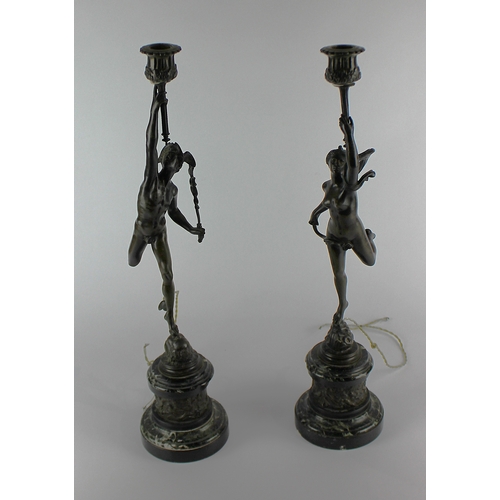 135 - A pair of 19th century dark patinated bronzed metal figural candlesticks, cast after Giambologna as ... 
