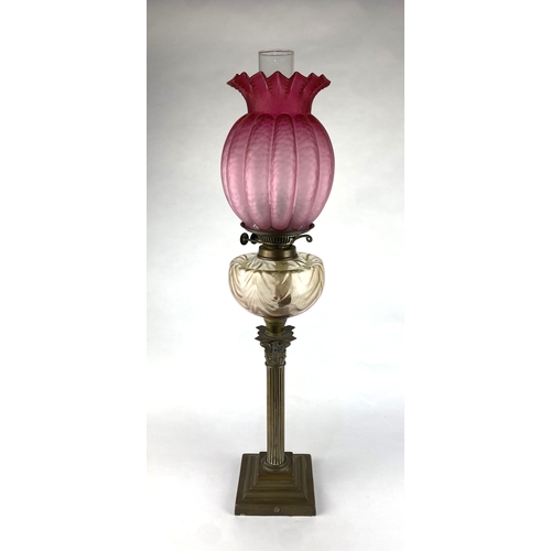 141 - A brass corinthian column oil lamp with swag moulded glass resevoir and cranberry glass shade, late ... 
