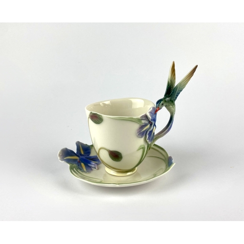 41 - A Franz porcelain teacup and saucer, by Wei Xeui Mei, modelled as an iris and hummingbird, variously... 