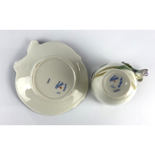 41 - A Franz porcelain teacup and saucer, by Wei Xeui Mei, modelled as an iris and hummingbird, variously... 