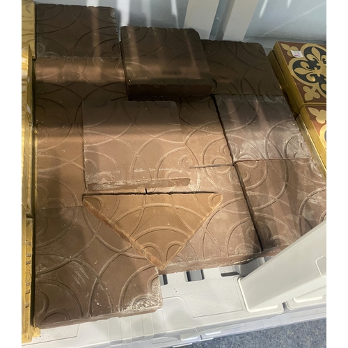 55 - Twenty-two dark red/ brown tiles inset with flower and circle design, 12.7cm by 12.7cm, and one corn... 