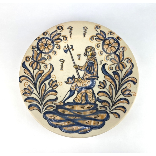 8 - A Spanish Talavera cermic charger, hand painted with a soldier sat on a rock amidst stylised foliage... 