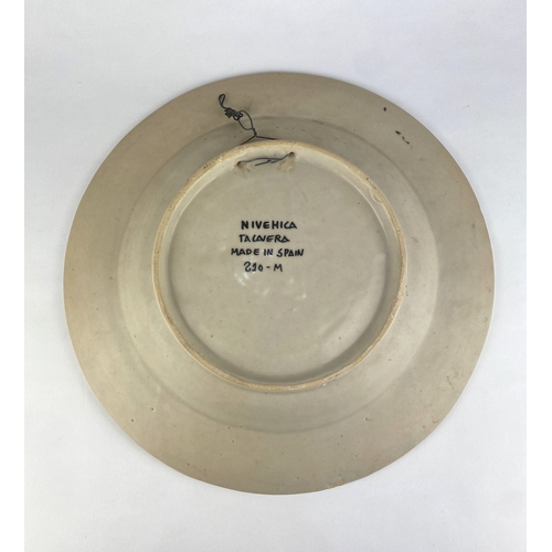 8 - A Spanish Talavera cermic charger, hand painted with a soldier sat on a rock amidst stylised foliage... 