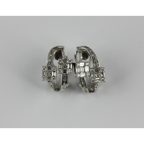 141 - A pair of white gold and diamond ear clips each in a twin square cluster and curved design, mounted ... 