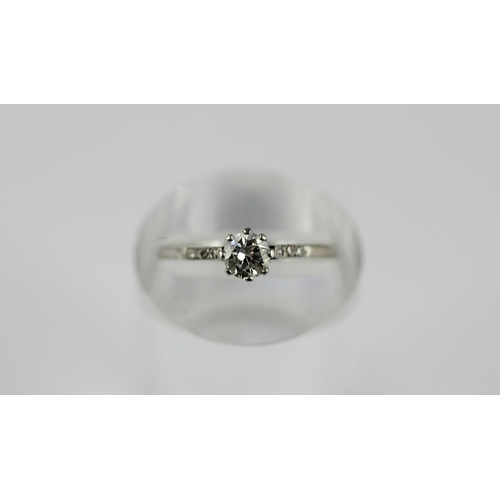 176 - A diamond ring claw set with the principal circular cut diamond at the centre, between diamond three... 