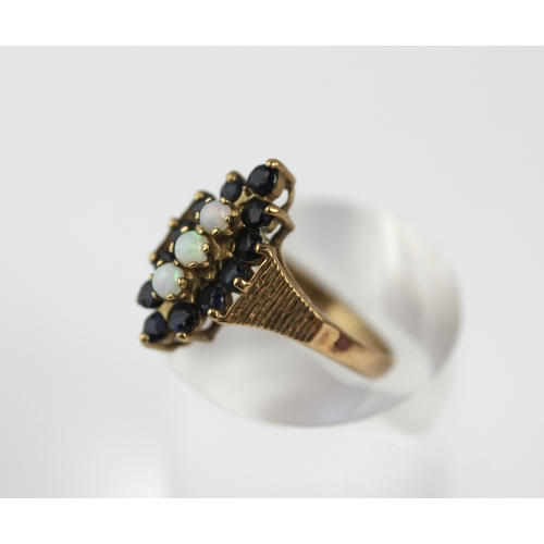 18 - A 9ct gold opal and sapphire marquise shaped cluster ring, set with three opals and with a surround ... 