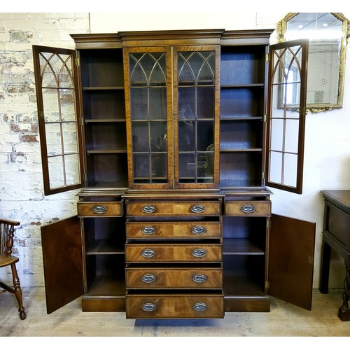 226 - A Regency Revival flamed mahogany breakfront library bookcase, oversailing cornice above three glaze... 