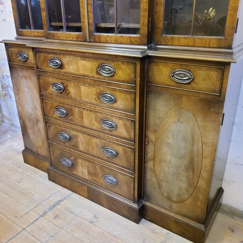 226 - A Regency Revival flamed mahogany breakfront library bookcase, oversailing cornice above three glaze... 