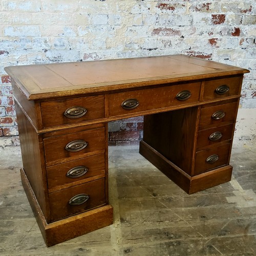 266 - An early 20th century oak knee hole pedestal desk, tooled leather inset surface above one long drawe... 