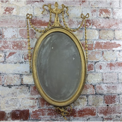 63 - A 19th century Neo Classical oval mirror, distressed ribbon tied swag decoration surmounted with urn... 