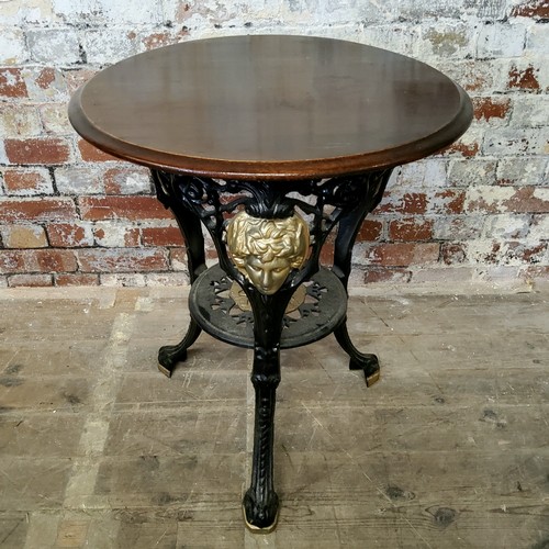 169 - A decorative cast iron tripod pub table, cast in relief with a classical mask design to base having ... 