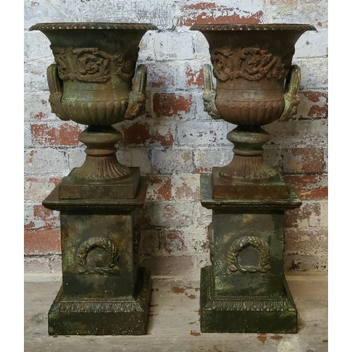 71 - A pair of Victorian cast iron campana shaped urns, raised on ribbon tied swag plinth 70cms high c.18... 