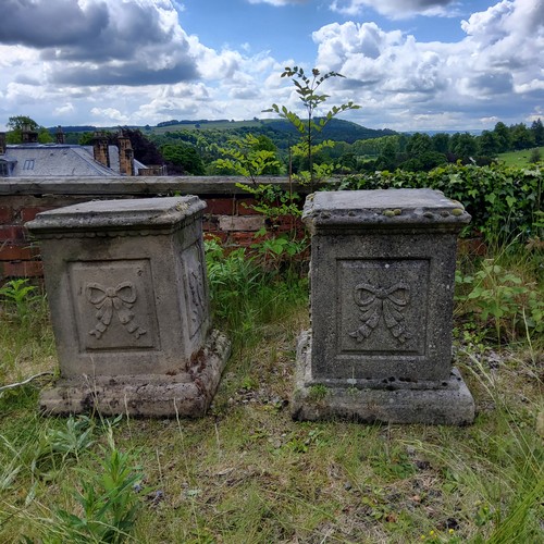 54 - A pair of reconstituted gritstone garden plinths, Neo Classical ribbon tied bow decoration to each s... 