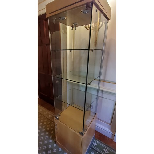 249 - A contemporary locking glazed display unit, enclosing three glass shelves on a beech veneered cupboa... 