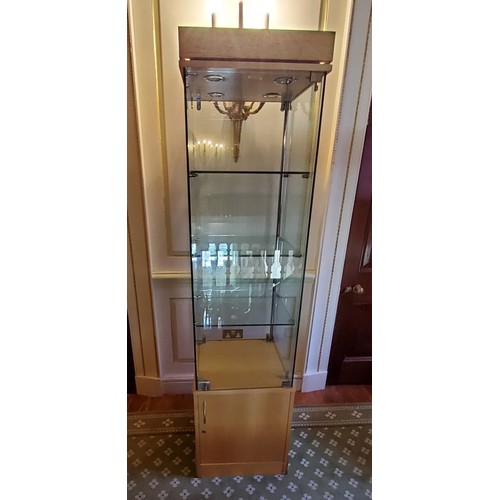 249 - A contemporary locking glazed display unit, enclosing three glass shelves on a beech veneered cupboa... 