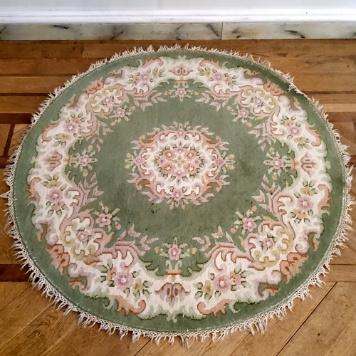 277 - A circular rug, in tones of apple green and a soft pink, 155cm diameter.