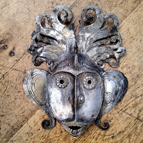 14 - An Indian silver plated metal wall mask of a deity with peacock headdress 31 x 26cms