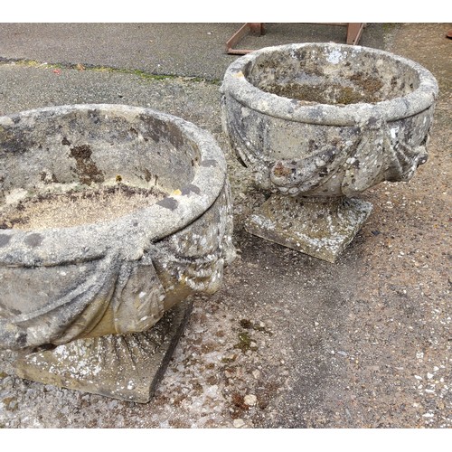 297 - A pair of squat cast concrete planters / urns with bows and fruits pattern. 34cm h x 37.5cm in dia