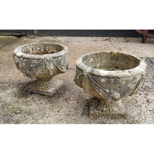 297 - A pair of squat cast concrete planters / urns with bows and fruits pattern. 34cm h x 37.5cm in dia