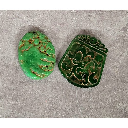 65 - Two Chinese jade amulet pendants, the oval amulet carved with monkeys on a rocky outcrop, yhe larger... 