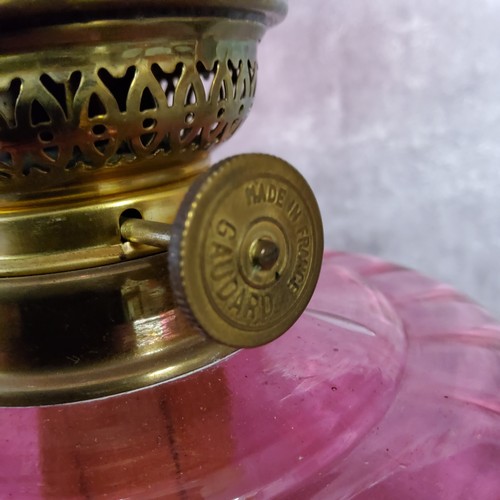 127 - A 19th century French cranberry glass and brass table oil lamp by Gaudard, with wavy ribbed shade ab... 