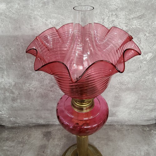 127 - A 19th century French cranberry glass and brass table oil lamp by Gaudard, with wavy ribbed shade ab... 