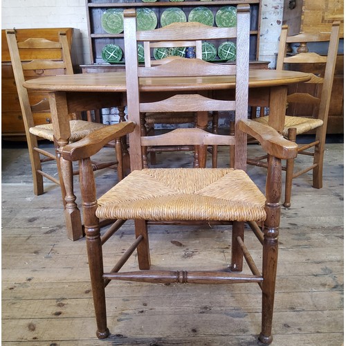 224 - A Nigel Griffiths English oak circular gate leg drop leaf dining table with four matching rush seate... 