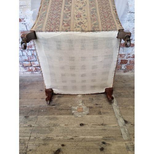 243 - A late Victorian Howard & Sons type armchair re-upholstered in chintz striped fabric, on mahogan... 