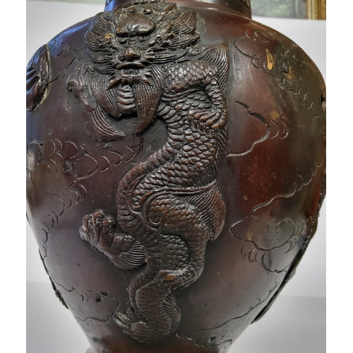 33 - A Japanese Meiji period bronze temple vase, decorated in relief with dragons, lacks handles.