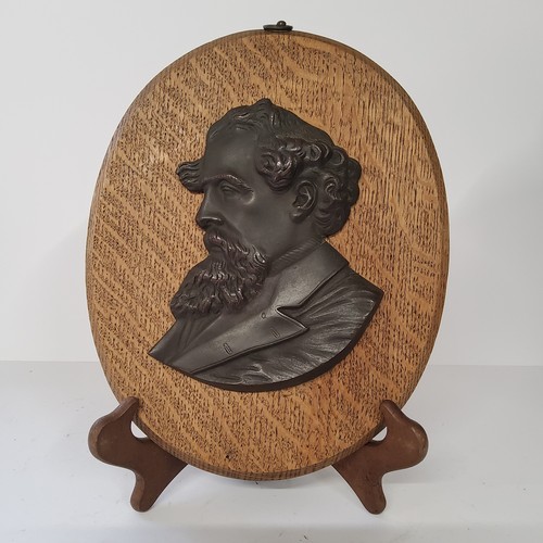 63 - Charles Dickens - a bronze bust mounted on an oval oak plaque. 28cm high. Excellent condition.