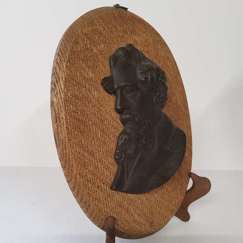 63 - Charles Dickens - a bronze bust mounted on an oval oak plaque. 28cm high. Excellent condition.