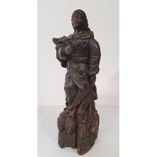 77 - An early 17th century Continental carved Saint figure raised on three cherubs to base. 40cm high