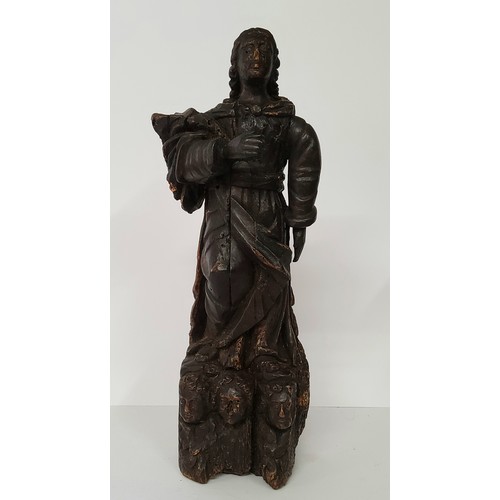 77 - An early 17th century Continental carved Saint figure raised on three cherubs to base. 40cm high