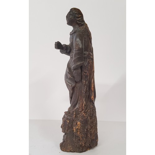 77 - An early 17th century Continental carved Saint figure raised on three cherubs to base. 40cm high