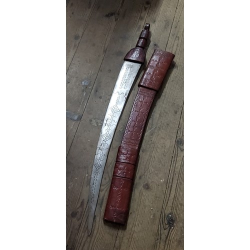 91 - A large South African tribal sword in embossed red leather sheath, the curved blade etched with deta... 