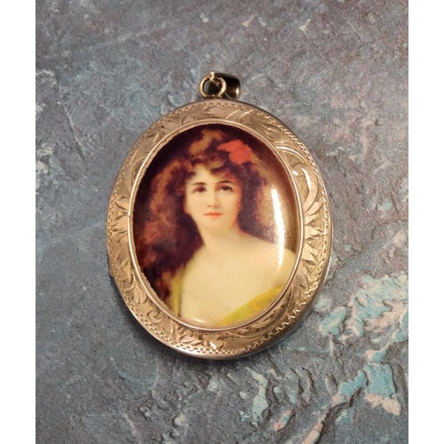 232 - A large oval silver locket the central raised panel set with an image of a maiden, engraved and chas... 