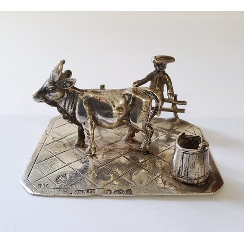 256 - A German silver miniature of a young farmer sat on a fence with his cow & milk pail, stamped 930... 