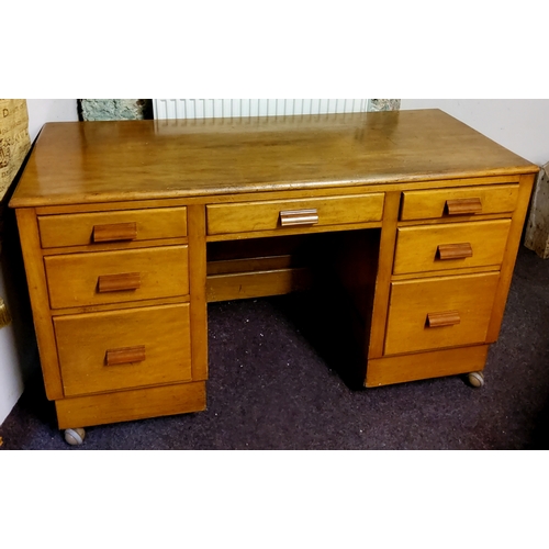 486 - An early 20th century teak kneehole desk with butterscotch amber Bakelite handles, castors.