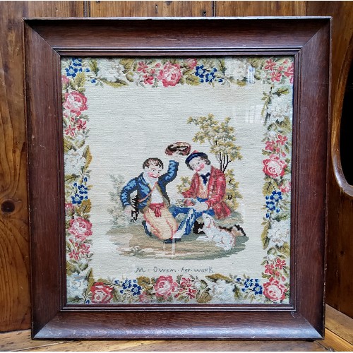 23 - A Victorian woolwork tapestry, embroidered with two Scottish boys and a dog, meandering floral borde... 